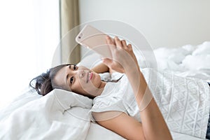 Woman using cellphone and lay down on bed