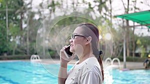 Woman using cellphone near the swimming pool.
