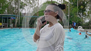 Woman using cellphone near the swimming pool.