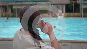 Woman using cellphone near the swimming pool, Waiting for her daughter.