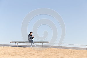 Woman using cellphone and sitting at bench