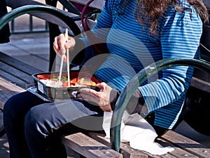 Woman Using Chopsticks eating Lunch on Bench