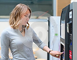 Woman using coffee vending machine.