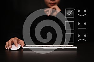 Woman using computer giving satisfied rating with smiley face icon to evaluate product and service.