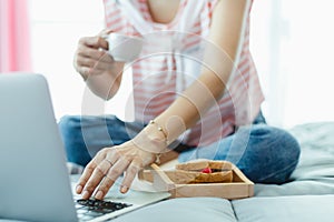 Woman using computer and having breakfast in bed for staying and working at home concept