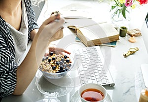 Woman using computer and having cereals