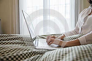Woman using computer laptop while wake up on bed in the morning