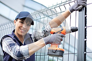 woman using cordless screwdriver to erect garden fence photo