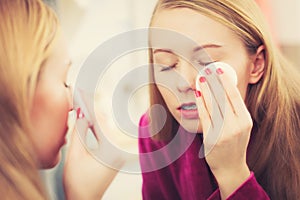 Woman using cotton pad to remove make up
