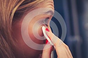 Woman using cotton pad to remove make up