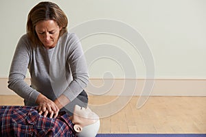 Woman Using CPR Technique On Dummy In First Aid Class