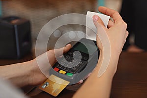 Woman using credit card machine for non cash payment in cafe, closeup