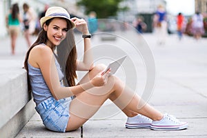 Woman using digital tablet on city street