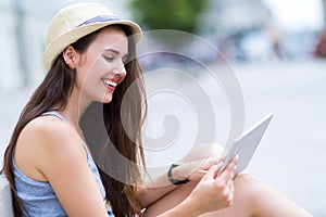 Woman using digital tablet on city street