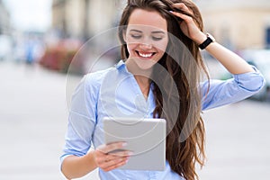 Woman using digital tablet on city street