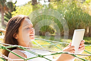 Woman using digital tablet in hammock at park