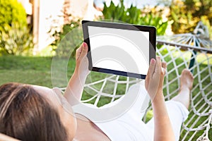 Woman using digital tablet in hammock at park