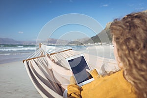 Woman using digital tablet while leaning at hammock