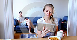 Woman using digital tablet while man using mobile phone