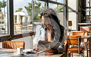 Woman using digital tablet and mobile phone while working in a coffee shop