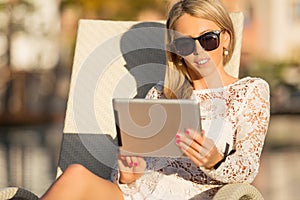 Woman using digital tablet while sitting in deck chair