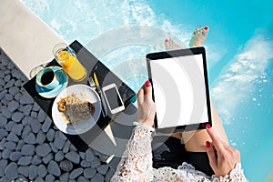 Woman using digital tablet while sitting in swimming pool