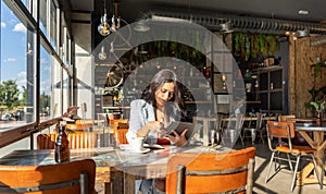 Woman using a digital tablet while working sitting in a coffee shop