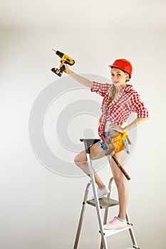 Woman using drill on ladder