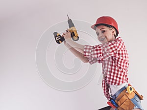 Woman using drill on ladder