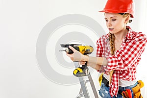 Woman using drill on ladder