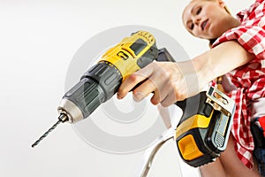 Woman using drill on ladder