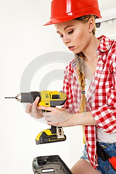 Woman using drill on ladder