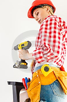 Woman using drill on ladder