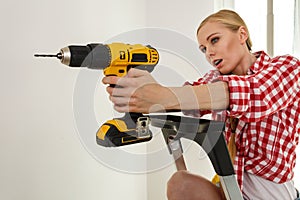 Woman using drill on ladder
