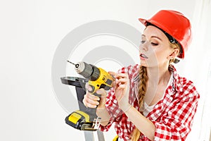 Woman using drill on ladder