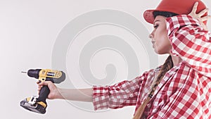 Woman using drill on ladder