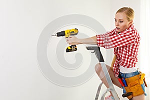 Woman using drill on ladder