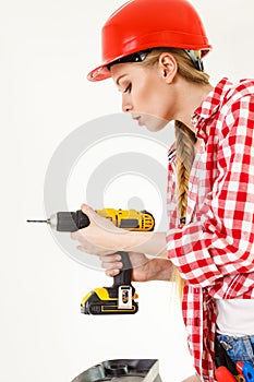 Woman using drill on ladder