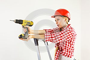 Woman using drill on ladder