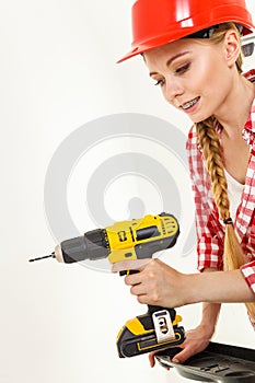 Woman using drill on ladder