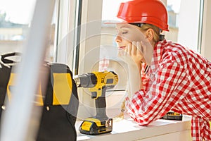 Woman using drill to fix or installing windows