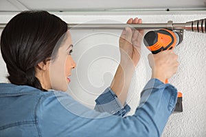 woman using drill to mount curtain rail support