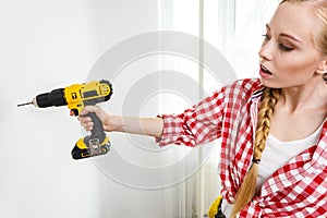 Woman using drill on wall