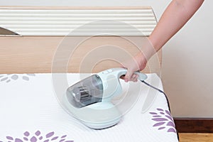 Woman using dust mites vacuum cleaner cleaning bed mattress