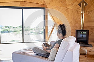 Woman using e reader while relaxing in a wooden dome tent.