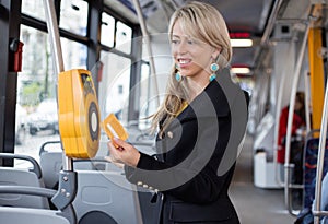 Woman using electronic ticket punching machine in public transport