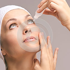 Woman using eye drops. Medicine treatment. Eyecare human problem. Ophtalmology dropper photo