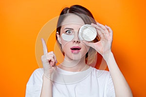 Woman using eye patch for her eyes and holding cream photo