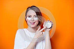 Woman using eye patch for her eyes and holding cream photo