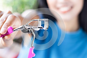 A woman is using eyelash curler